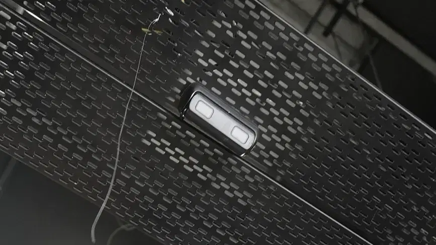 Close-up of a dual-lens analytics camera mounted on a cable tray under a warehouse roof