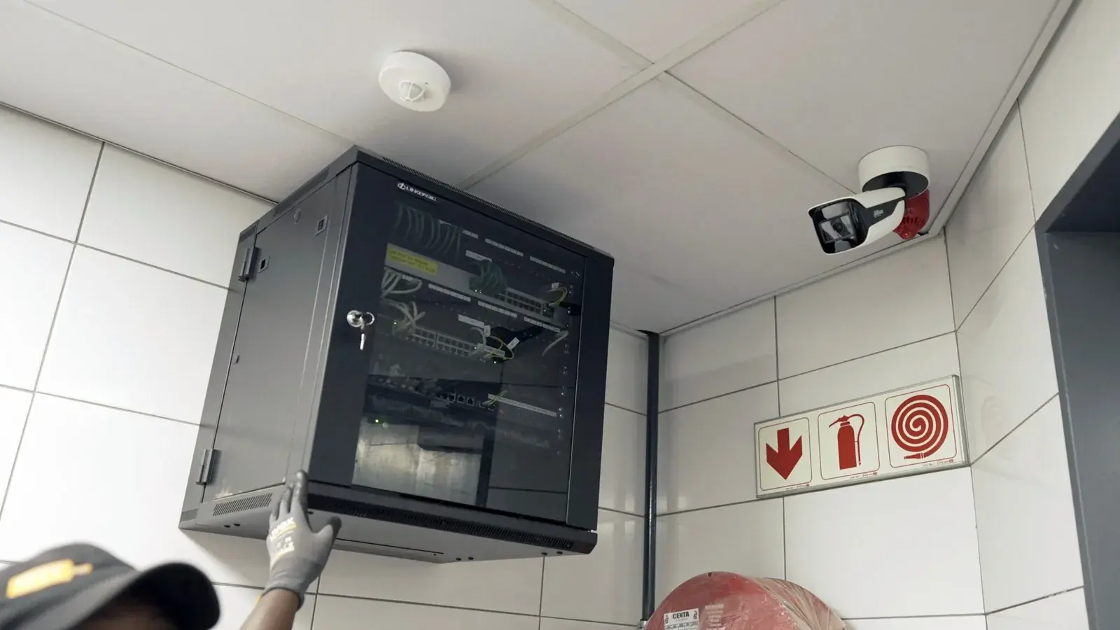 Wall-mounted CCTV network cabinet and a bullet camera installed in a tiled service room